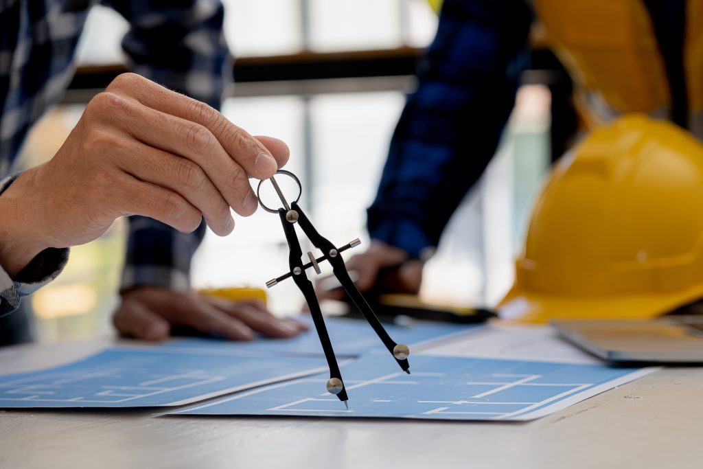 Architects use compasses to draw on building plans for editing, architect engineers design houses and interior structures and draw plans through design programs. Architect concept of building design.