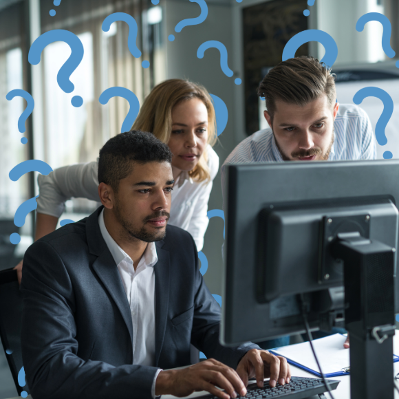 Symbolische Darstellung von Fragestellungen im Unternehmen. Ein divers besetztes Team, bestehend aus einem Mann in dunklem Sakko, einer Frau und einem weiteren Mann, konzentriert sich gemeinsam auf einen Computerbildschirm. Ihre Haltung drückt Nachdenklichkeit und die Suche nach Lösungen aus. Um die Personen herum schweben zahlreiche stilisierte, hellblaue Fragezeichen, die die Komplexität der Aufgabe oder Unklarheiten bei der Arbeit symbolisieren.